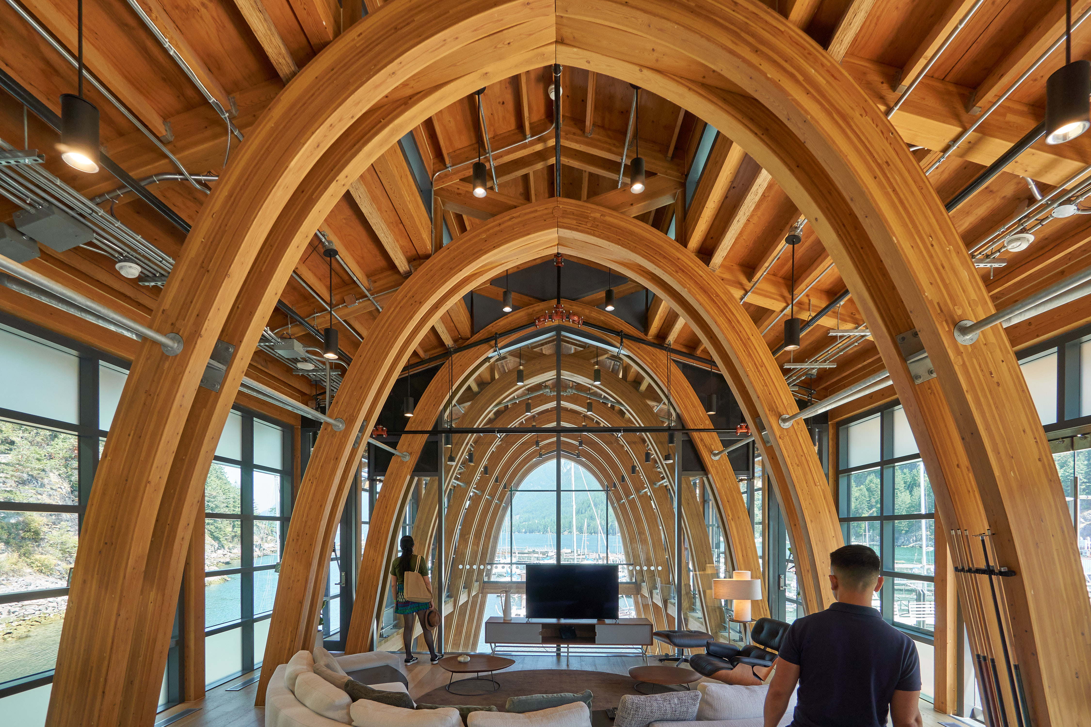 A large living room space with a wooden interior and several large, high wooden arcs over the furniture.